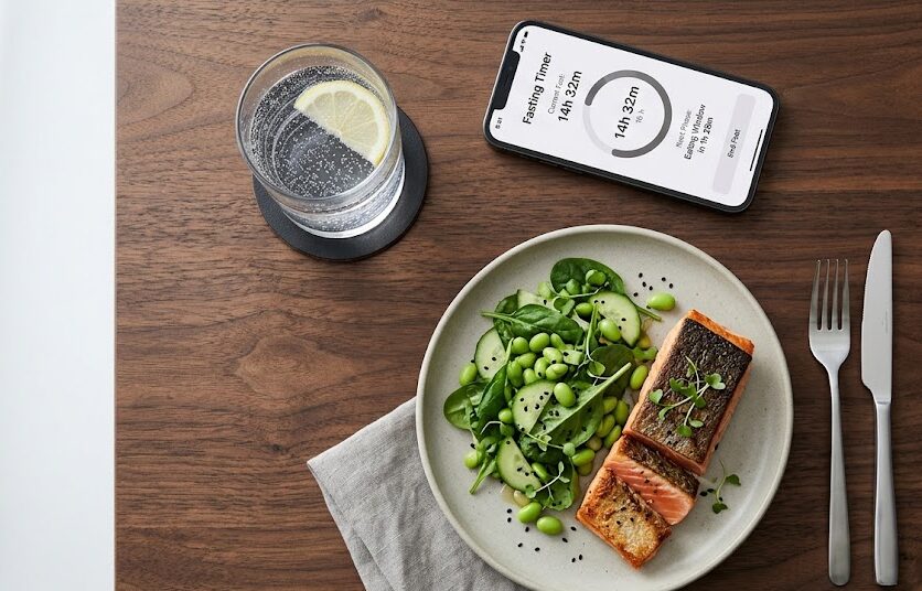 How to Naturally Increase HGH: A healthy meal alongside a timer app, representing the metabolic benefits of intermittent fasting for HGH release.